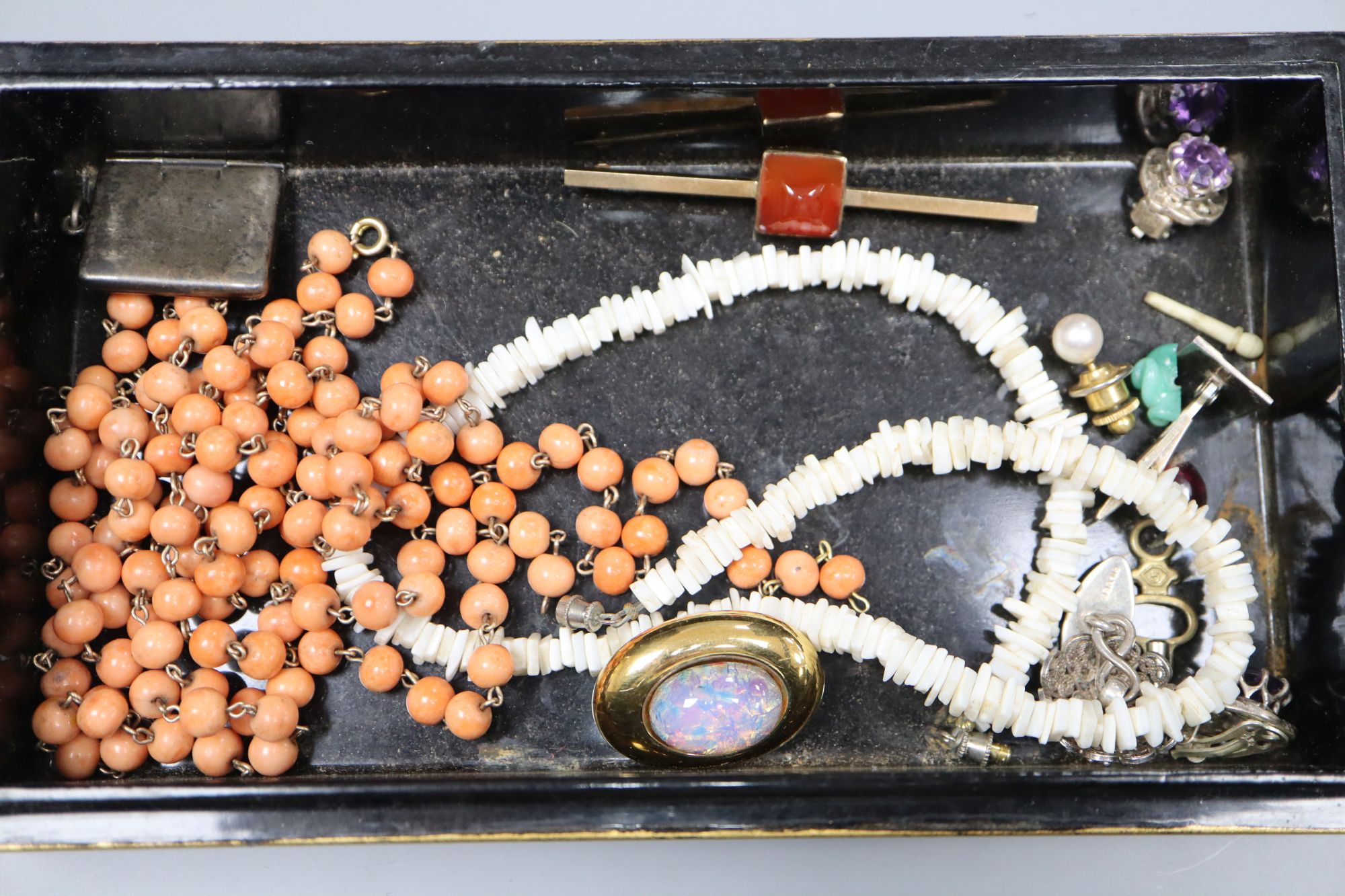 A 9ct and carnelian set tie pin, an Edwardian silver stamp envelope, Chester, 1905(splits), a coral bead necklace, etc.